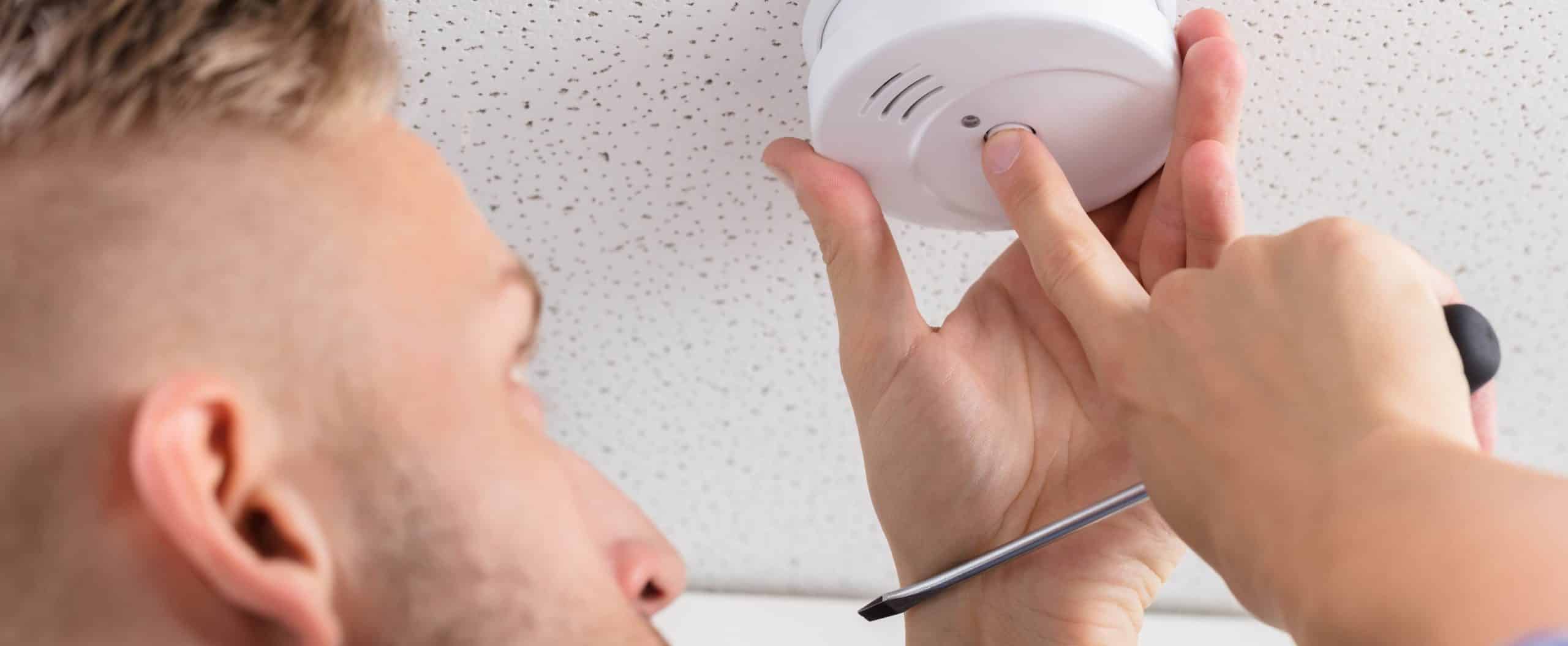 man checks carbon monoxide detector