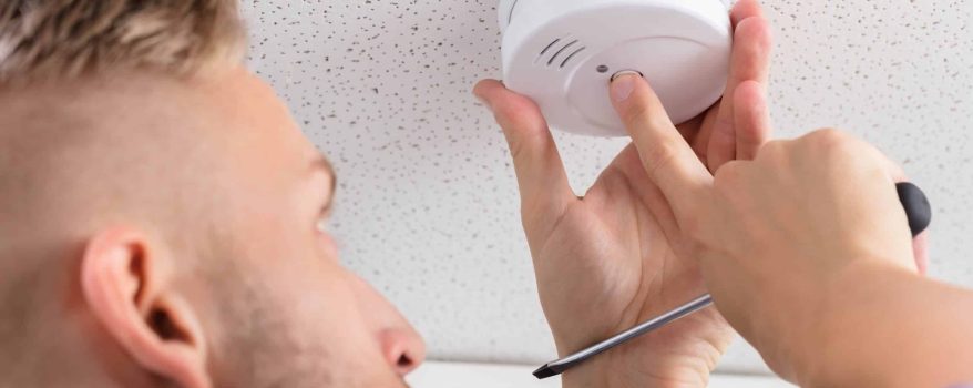 man checks carbon monoxide detector